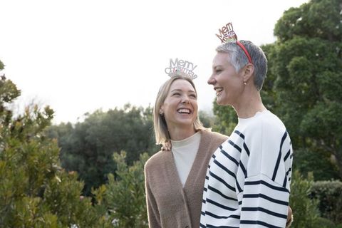 Mature women laughing outdoors wearing merry christmas headbands