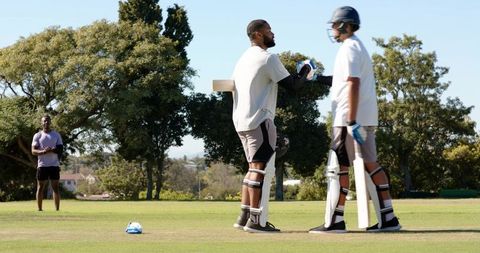 African american batter celebrating half-century with teammate on sunny cricket field
