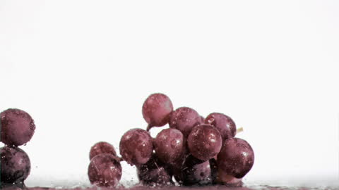 Purple Grapes Splashing in Water Against White Background