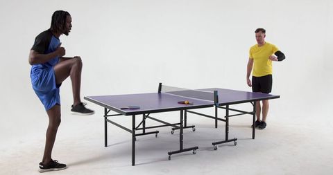 Energetic Men Practicing Sporty Footwork Around Ping Pong Table