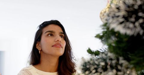 Woman Admiring Festive Evergreen Tree at Home