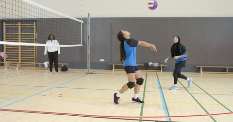 Female volleyball players practicing forearm pass in indoor gym showcasing teamwork
