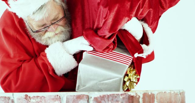 Santa Claus placing a wrapped gift in a chimney with a sack of presents. Festive holiday scene perfect for Christmas-related content, advertisements, card designs, or social media posts celebrating Christmas and gift-giving.