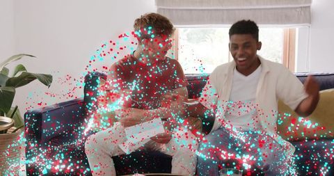 Friends celebrating surprise unboxing with colorful confetti overlay on couch at home