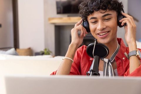 Young Man in Home Studio Enjoys Podcasting with Microphone and Headphones