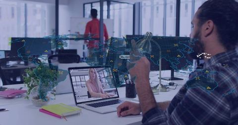 Remote team collaborating via laptop and mobile with global map overlay in modern office