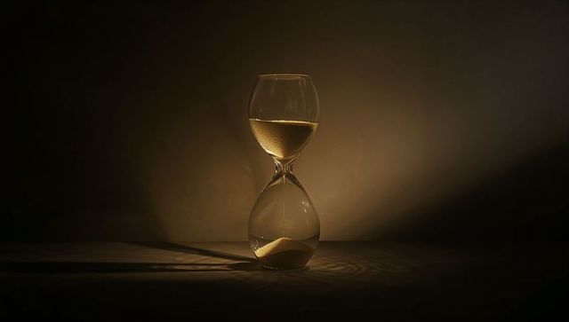Elegant hourglass with golden sand in dim light