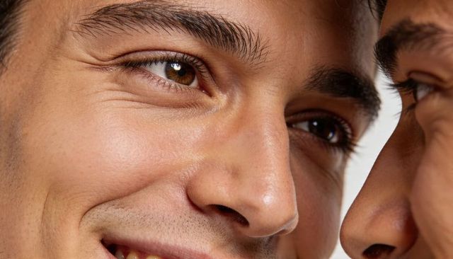 Men smiling close-up showing natural skin texture, stubble, eyebrows and eyes