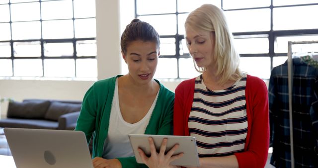 Two female colleagues discussing work using digital tablet in modern office - Download Free Stock Images Pikwizard.com