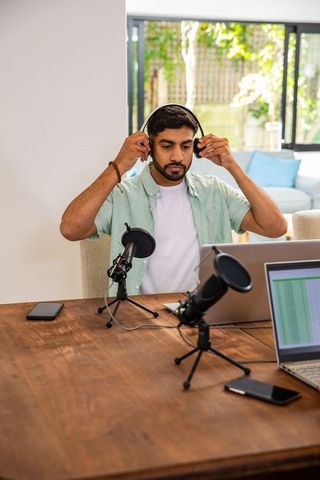Man preparing podcast with microphones and laptop at home studio