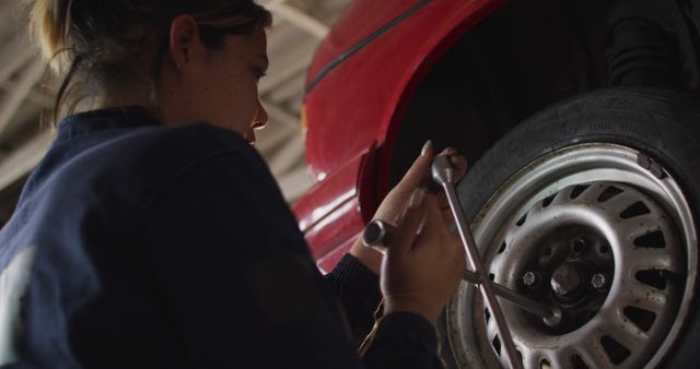 Female mechanic changing tires of the car using a wheel wrench at a car service station. automobile repair service concept