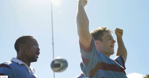 Rugby players celebrating try, raising arms in victory on sunny outdoor pitch
