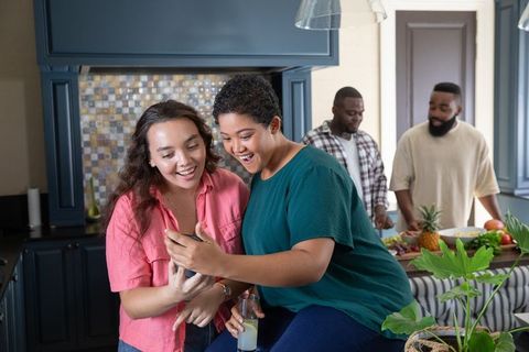 Friends Connecting Over Smartphone During Kitchen Gathering
