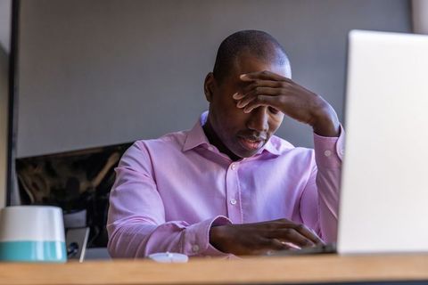 Stressed businessman with laptop in modern office