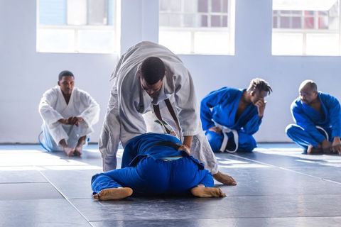 Experienced Martial Artist Demonstrating Techniques to Trainees in Dojo