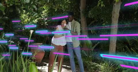 Couple holding calla lily on garden path with neon light streaks, romantic casual moment