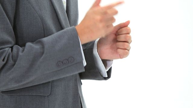 Person in formal suit is signing against a white backdrop, emphasizing expressive communication. Ideal for use in articles about non-verbal communication, professional business settings, inclusivity in workplaces, or educational materials about sign language.