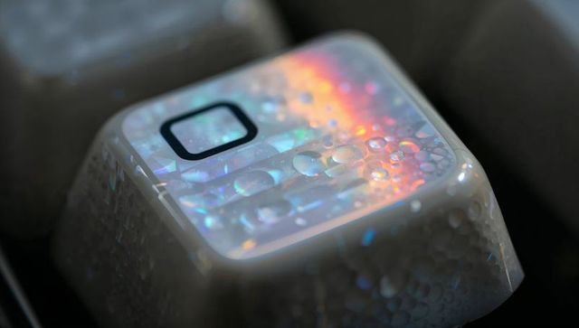 Glowing white keycap holding water droplets and rainbow refraction macro iridescent bokeh