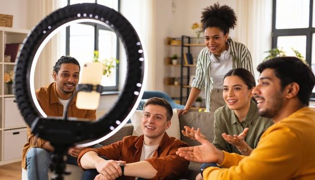 Young multicultural creators recording livestream with ring light and smartphone at home