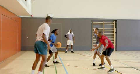 Men playing pickup basketball indoors practicing defense and dribbling on hardwood court