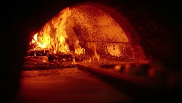 Rustic wood fire inside traditional brick oven