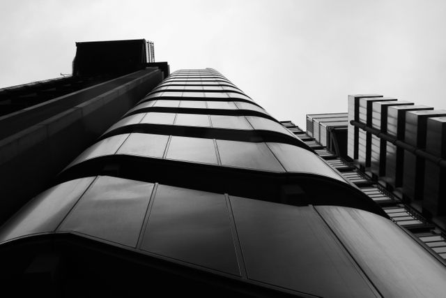 Modern skyscraper architecture shot from a low angle in black and white, highlighting the structure's sleek and contemporary design. This image is ideal for use in corporate presentations, architectural portfolios, urbanization studies, and minimalistic design projects.