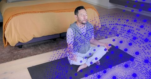 Asian man meditating on yoga mat beside orange duvet with blue overlay calm wellness