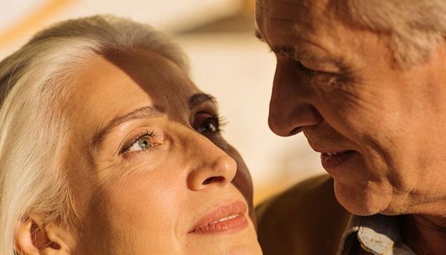 Senior couple sharing tender close embrace, warm intimate gaze, mature love and connection
