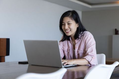 Woman Using Laptop for Work in Modern Dining Space