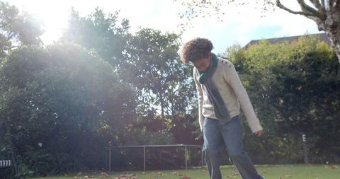 Joyful boy in autumn garden with fallen leaves