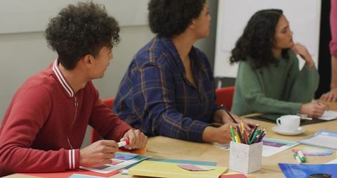 Young team brainstorming and collaborating around wooden table with colorful papers