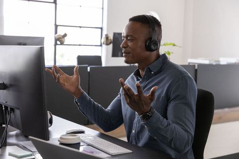African American professional gesturing during video call in modern office with headset