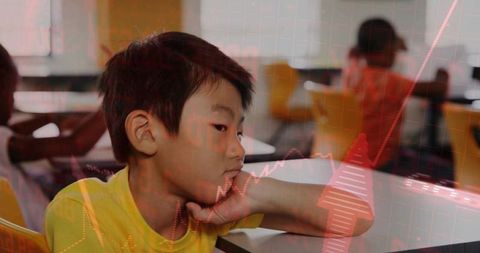 Thoughtful asian boy leaning chin on hand in bright classroom, school learning moment