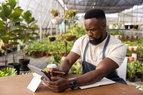 Mid-adult african american greenhouse owner working on tablet planning nursery operations