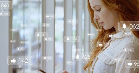 Red-haired woman checking smartphone with social notifications in sunlit coworking space