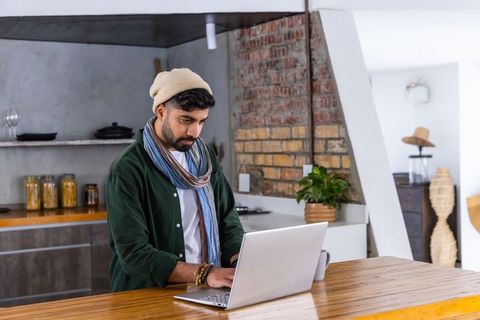 Working remotely at rustic kitchen island man using laptop from modern industrial home