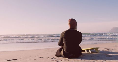 Man in Wetsuit Relaxing by Beach with Ocean View - Download Free Stock Images Pikwizard.com