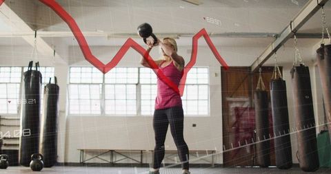 Athletic woman swinging kettlebell in gym with red data chart overlay for fitness analytics