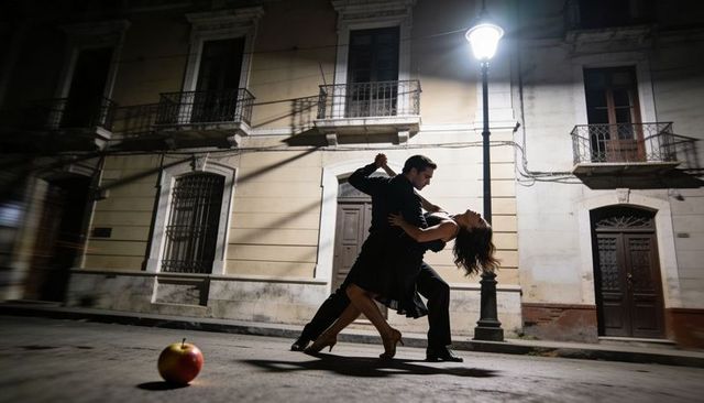 Couple dancing tango under streetlight on quiet urban street at night with cinematic lighting