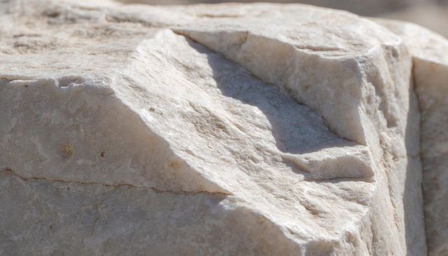 Sunlit pale marble rock showing concave groove and natural mineral flecks texture