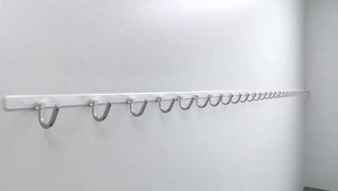 Chrome u-shaped hooks lining white wall, repeating wall rail for minimalist storage