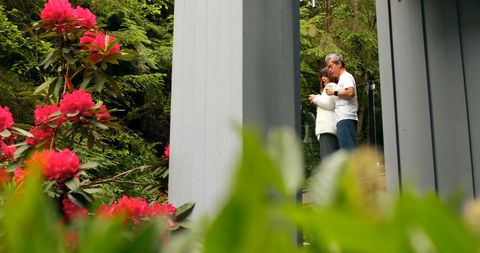 Couple Embracing in Home Garden Surrounded by Flowers