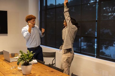 African american coworkers celebrating big win in modern office meeting room, team spirit