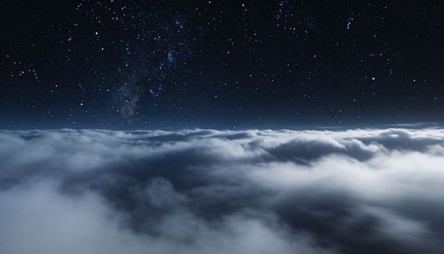 Milky way above rolling night clouds - mystical ethereal starry sky over ocean of clouds
