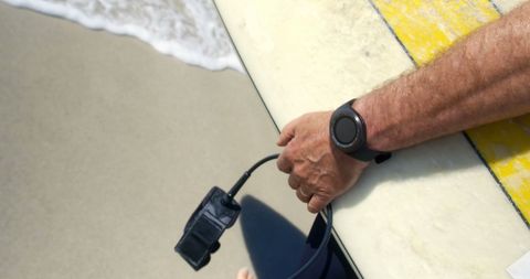 Surfer Carrying Board on Sandy Beach, Wearing Smart Watch