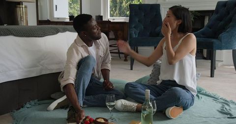 Diverse Couple Relaxing Together in Bedroom with Picnic Setting