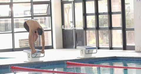 Male Athlete Preparing to Dive at Indoor Swimming Pool for Practice