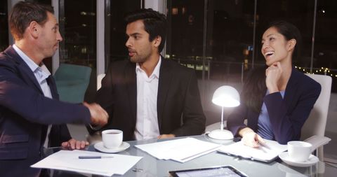 Business Professionals Shaking Hands in Modern Night Office