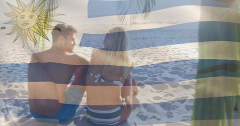 Couple sitting on sunlit beach with uruguay flag overlay celebrating summer romance