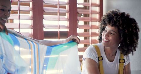 African American Women Sharing Colorful Fabric at Home